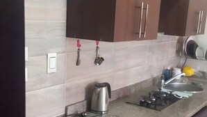 A modern kitchen with wooden cabinets, a stainless steel kettle, a sink, and a trash bin. - Cozy chalet in beautiful الغردقة with AC, WiFi, fitness room (الغردقة)