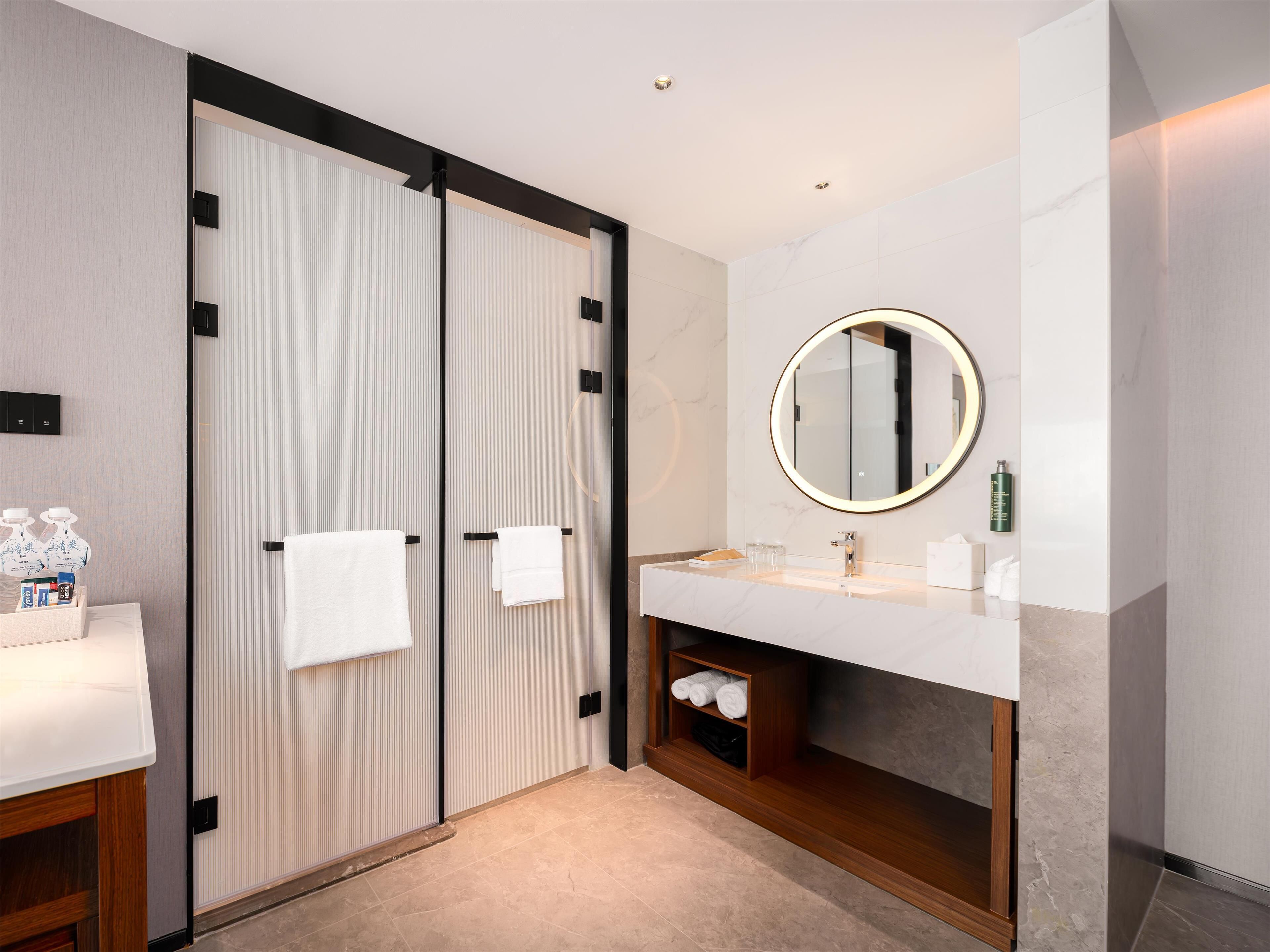 A modern bathroom with a large mirror, a sink, and a towel rack.