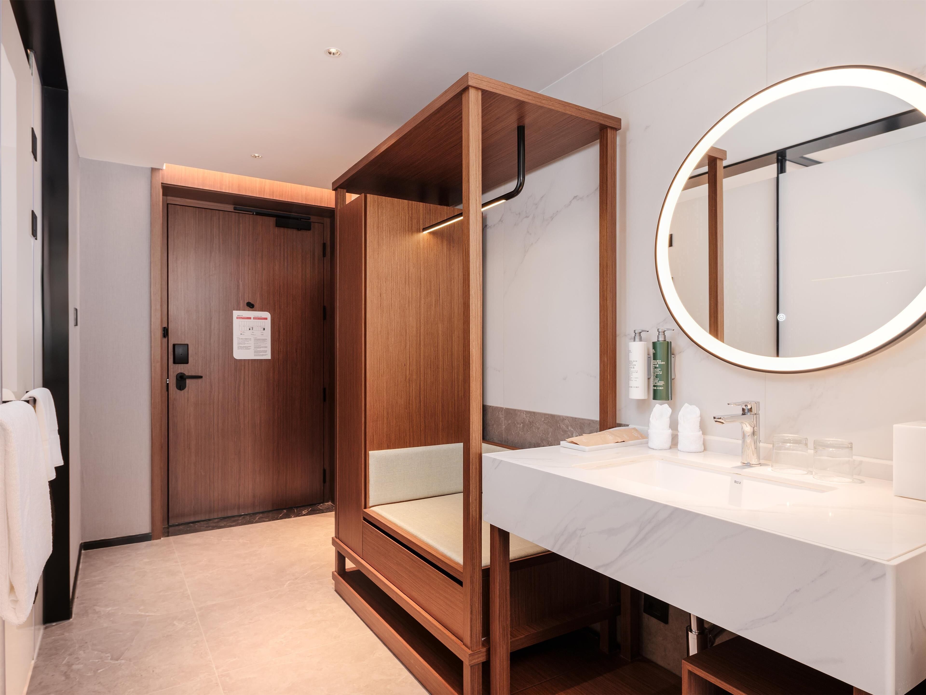 A modern bathroom with a wooden vanity, a large mirror, and a toilet.