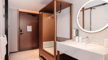 A modern bathroom with a wooden vanity, a large mirror, and a toilet.