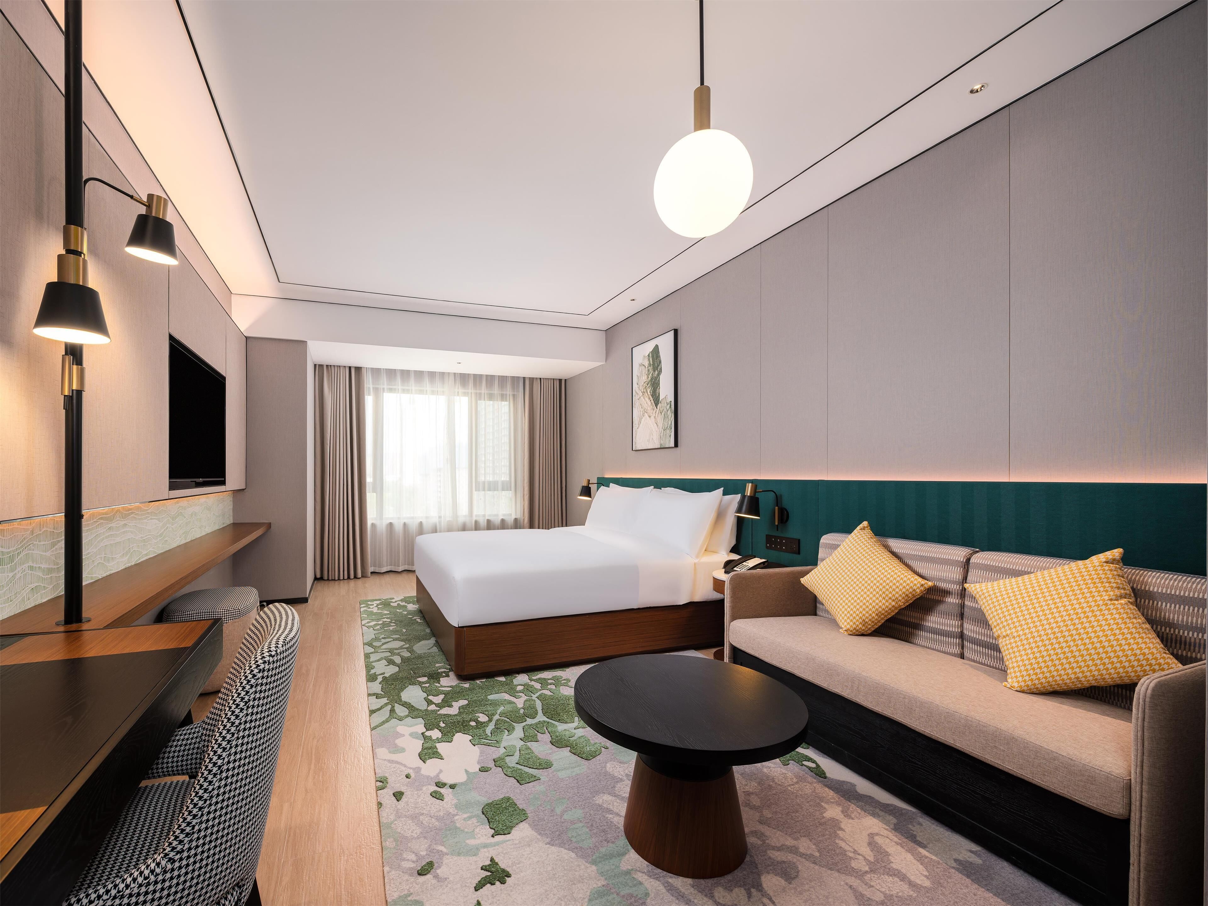 Een moderne hotelkamer met een groot bed, een bank, een salontafel, een bureau en een televisie.