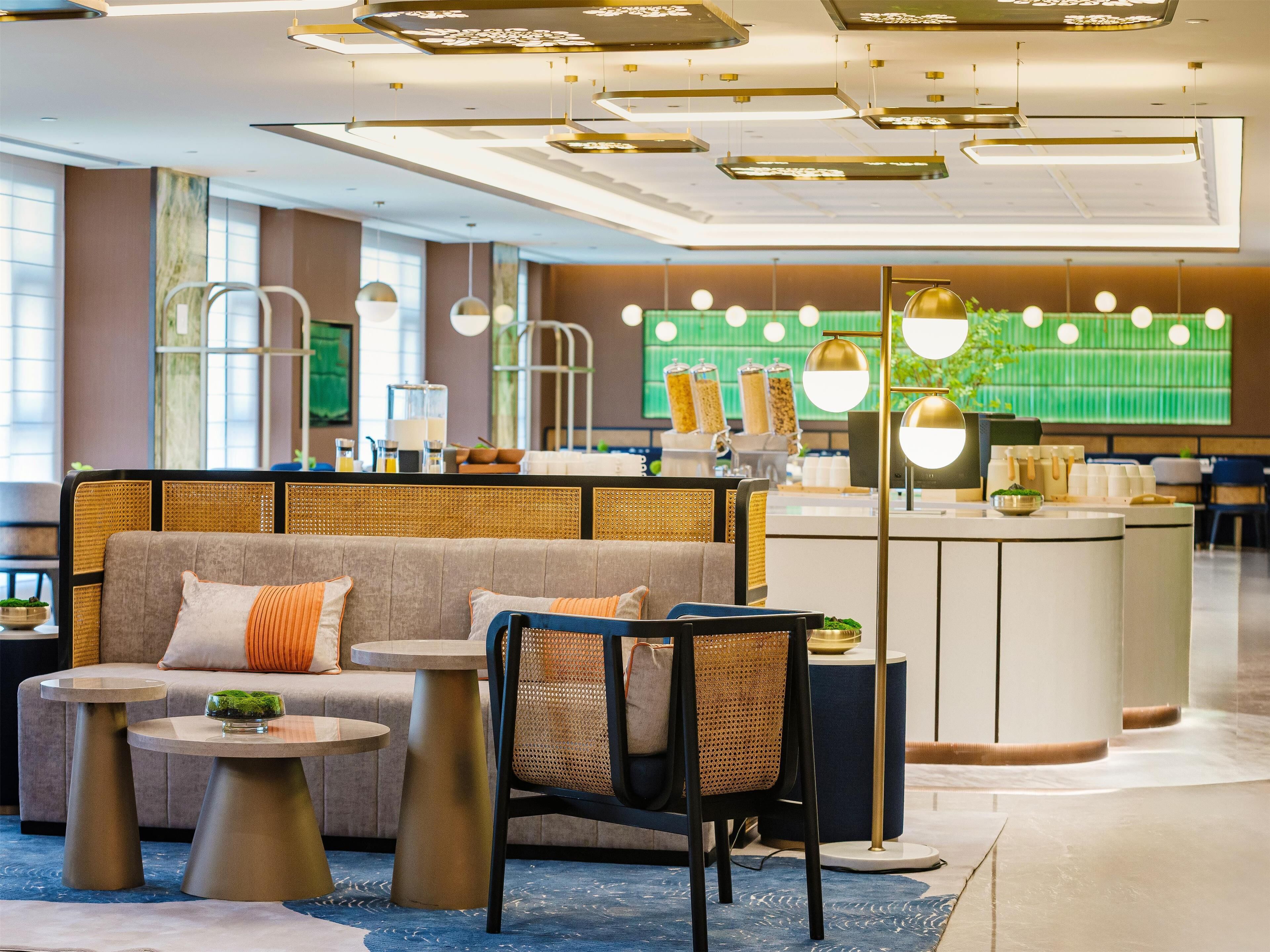 Eine moderne Hotellobby mit einer Sitzecke, einem Empfangsbereich und einer großen, grünen Wand mit Wandgemälde eines Sportfelds.