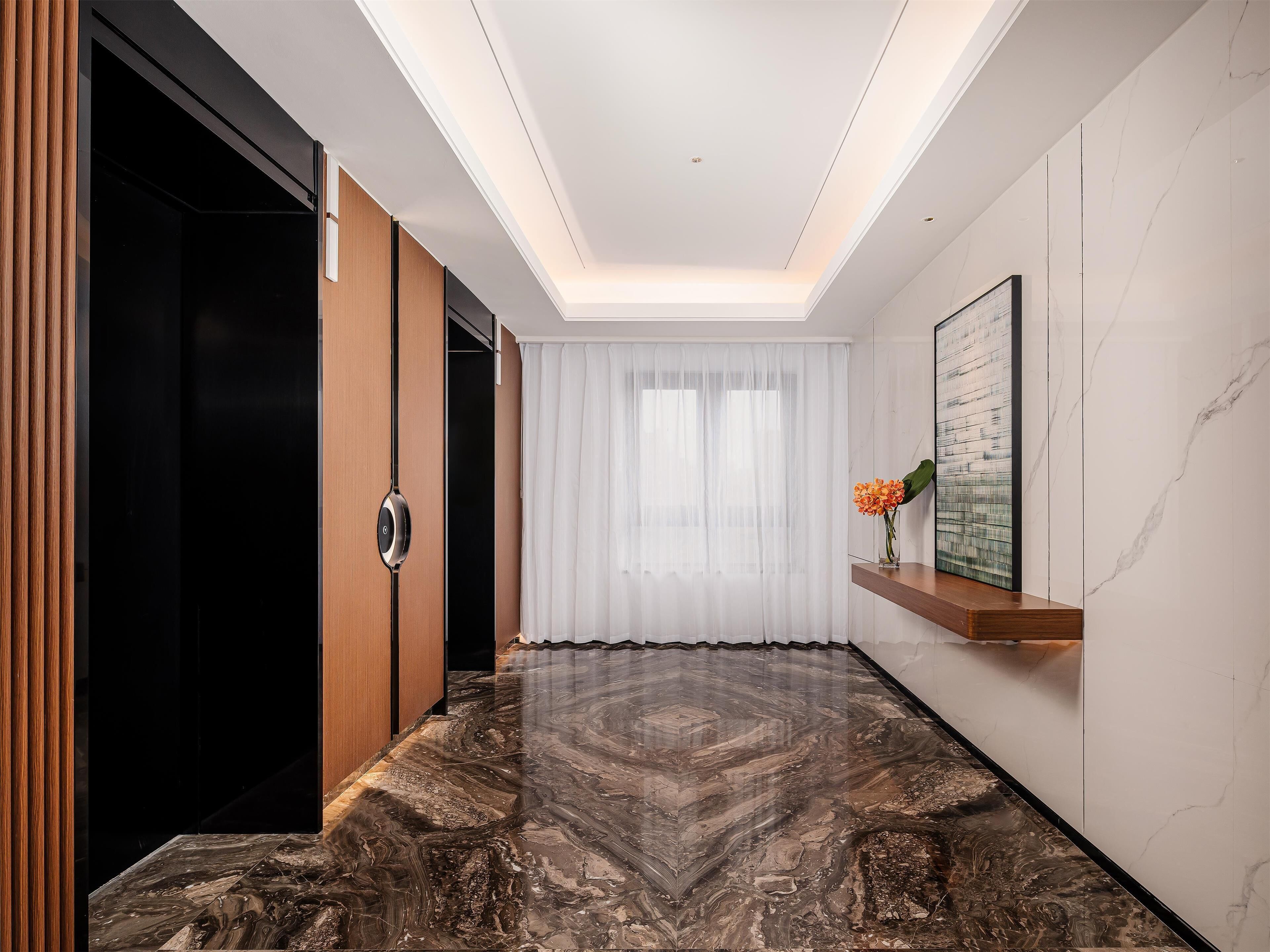 A modern hallway with a marble floor, wooden doors, a white curtain, and a framed artwork on the wall.