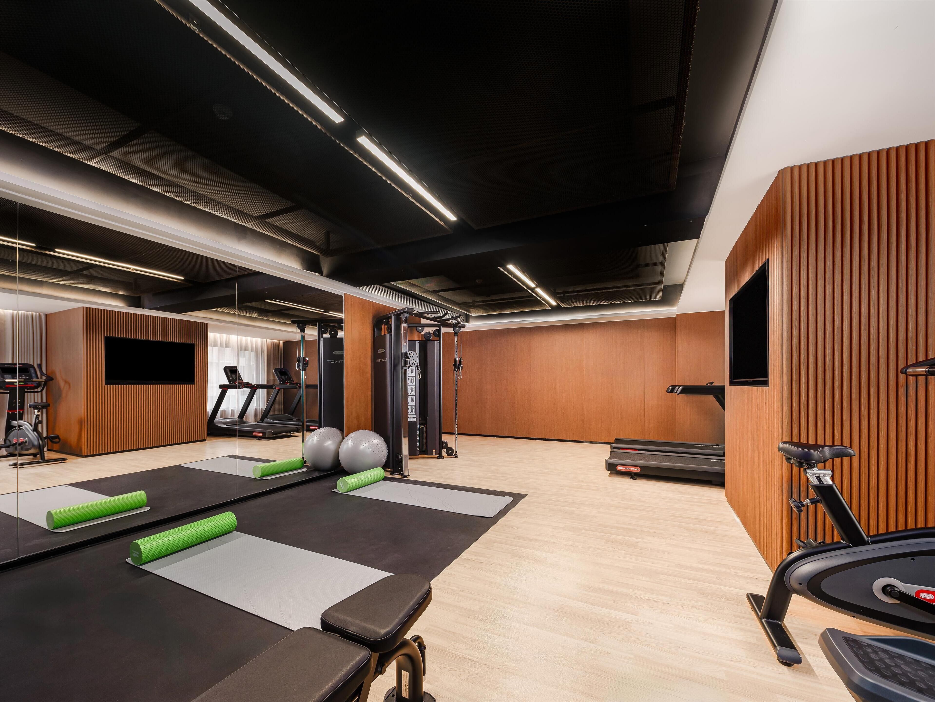 Ein modernes Fitnessstudio mit Trainingsgeräten, Laufband und einer Spiegelwand.