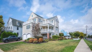 A two-story residential house with a front porch, a driveway, and a well-maintained lawn. - Spacious 4BR Home near Cape May Beach | Sleeps 10! (Cape May)