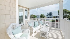 A covered porch with wicker furniture and a view of the neighborhood. - Spacious 4BR Home near Cape May Beach | Sleeps 10! (Cape May)