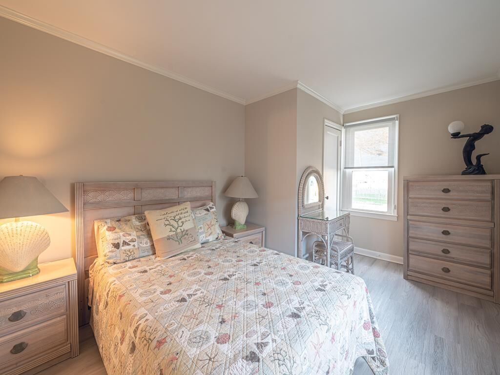 A bedroom with a bed, nightstands, a dresser, and a window.