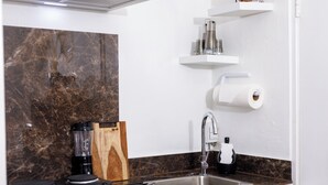 A modern kitchen with a marble backsplash, a built-in coffee maker, a sink, and a knife block. - Cozy small studio room in Julianadorp with own bathroom and kitchenette (Willemstad)