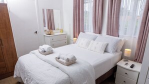 A neatly made bed with white linens, a bedside table with a lamp, and a wooden wardrobe. - Cozy small studio room in Julianadorp with own bathroom and kitchenette (Willemstad)