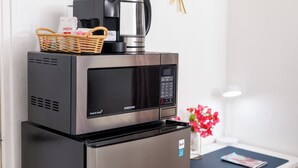 A Samsung refrigerator with a microwave on top, a basket with coffee pods, and a coffee maker. - Cozy small studio room in Julianadorp with own bathroom and kitchenette (Willemstad)