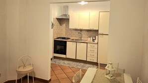 Une cuisine de taille réduite, équipée d’une cuisinière à gaz, d’un évier et de meubles blancs.