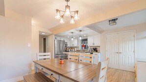 A modern kitchen with white cabinets, a wooden dining table, and a built-in oven. - Modern 3-bedroom Escape in Northwest Reno (Reno)
