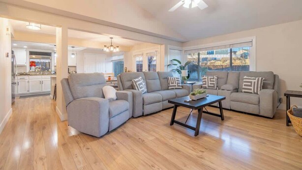 A spacious living room with a grey sectional sofa, a coffee table, and a ceiling fan. - Modern 3-bedroom Escape in Northwest Reno (Reno)