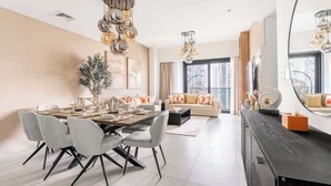 Een moderne woonkamer met een eethoek, grote ramen en een zwarte entertainmentkast.