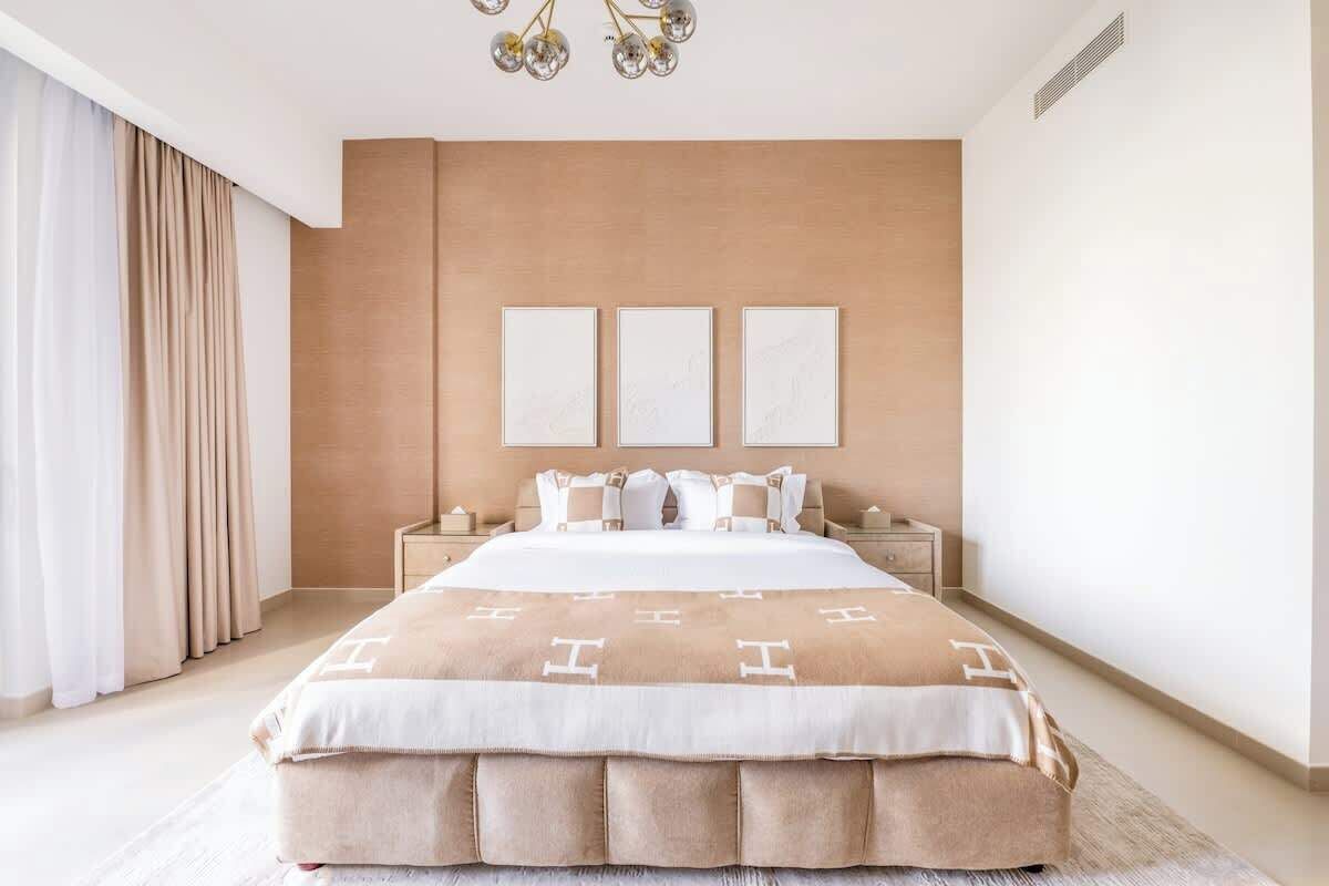 A modern bedroom with a large bed, a neutral color scheme, and a minimalist design.