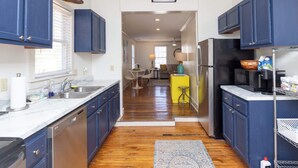 A modern kitchen with blue cabinets, a stainless steel refrigerator, and a wooden floor. - The Place on Pierce by Apex Short Term Stays (Oxford)