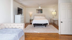 A bedroom with a bed, a TV on a dresser, a bedside lamp, and a door. - The Place on Pierce by Apex Short Term Stays (Oxford)