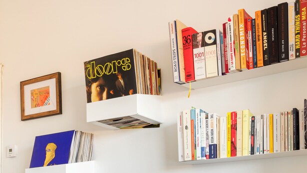 Un salon moderne doté d’un téléviseur à écran plat, d’une platine vinyle et d’une bibliothèque remplie de livres et de CD.