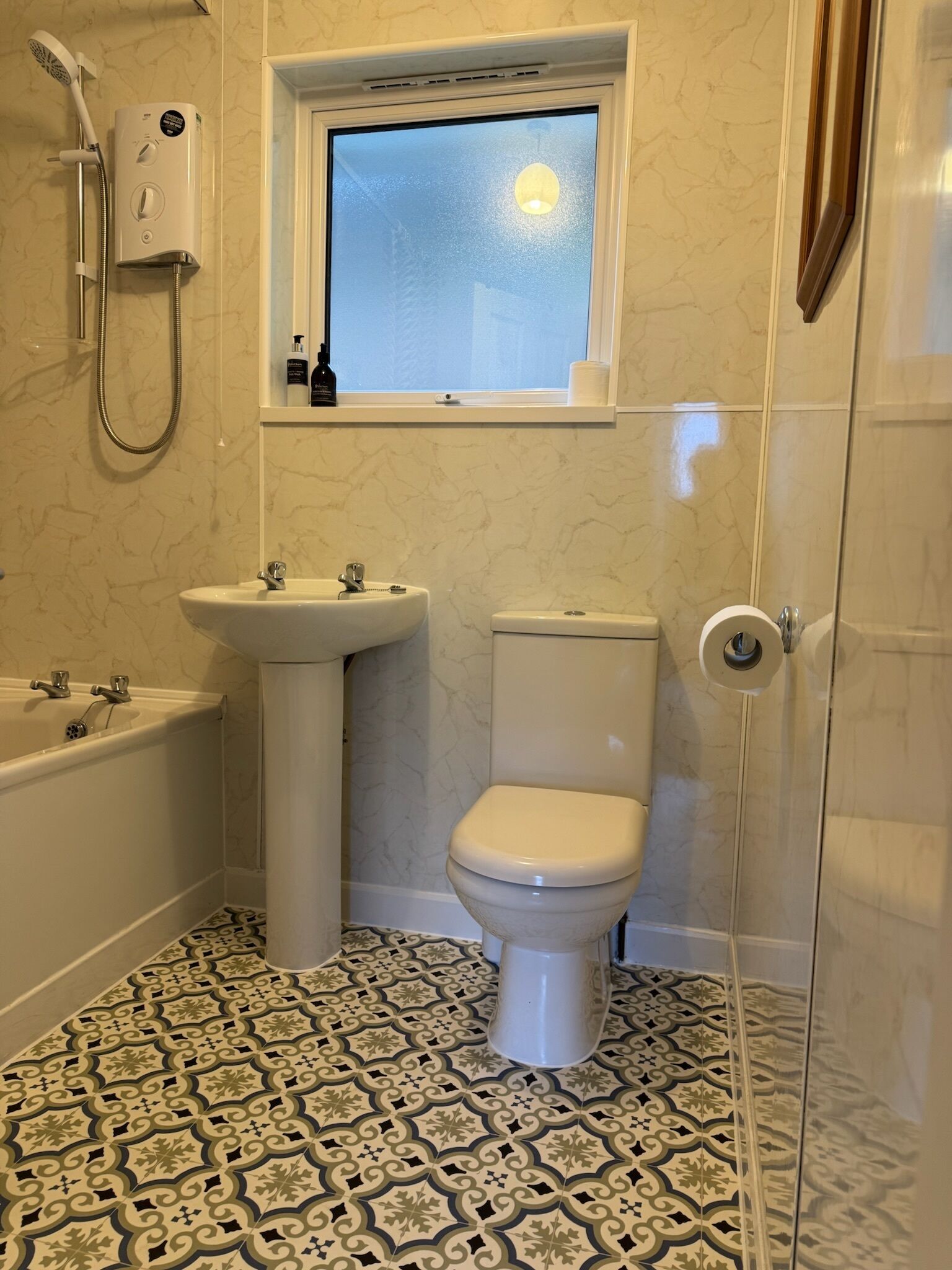 A bathroom with a bathtub, sink, toilet, and a window above the toilet.