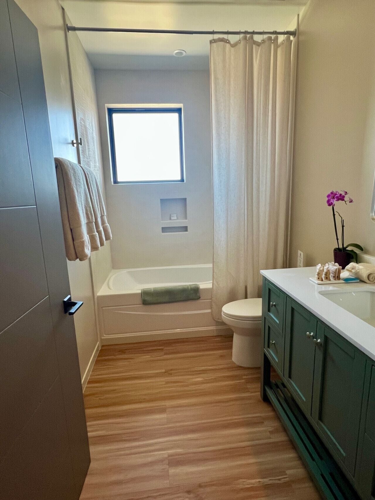 A bathroom with a bathtub, toilet, and a window.