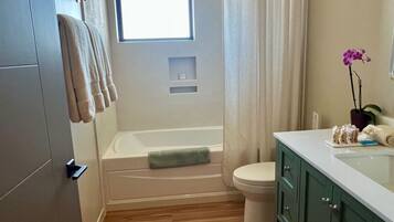 A bathroom with a bathtub, toilet, and a window.