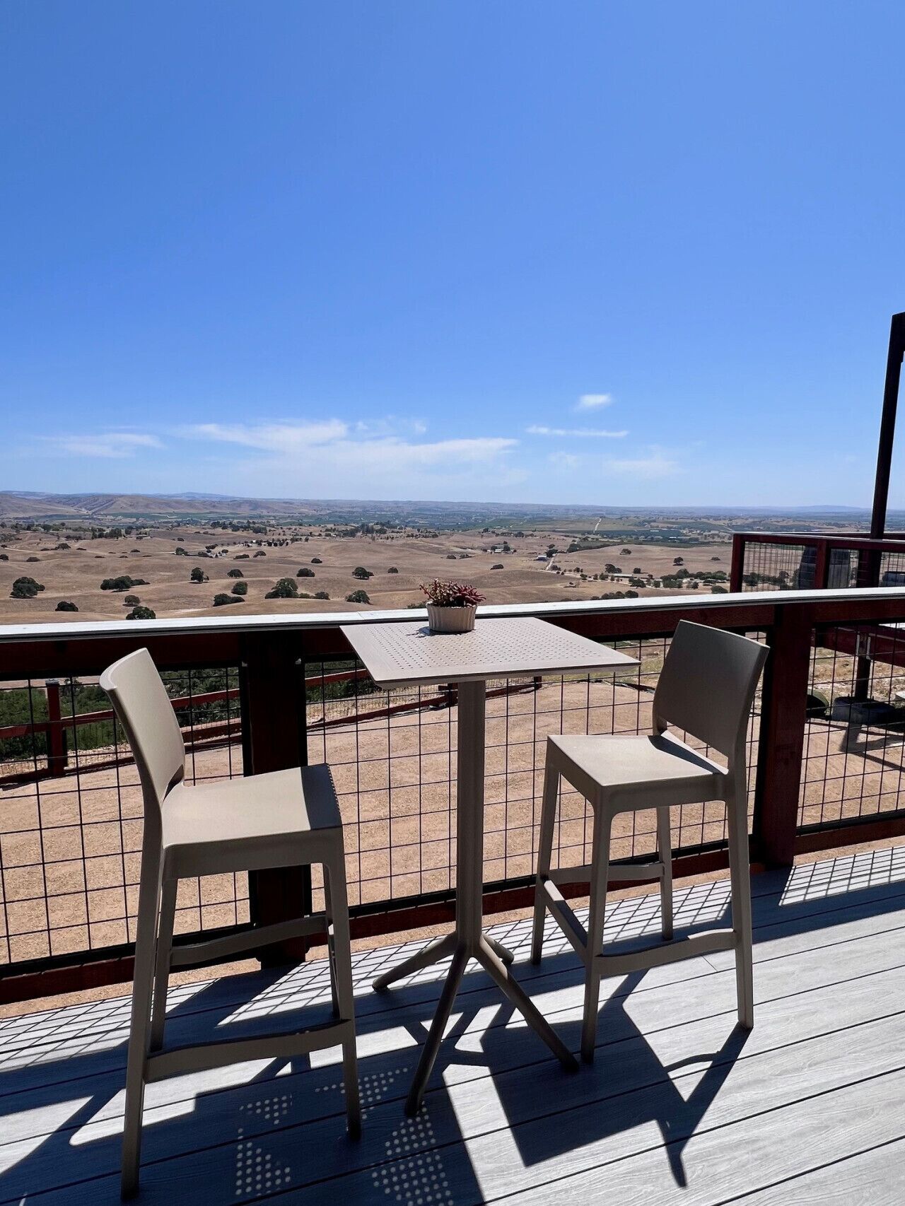 Um terraço com duas cadeiras e uma mesa, com vista para uma paisagem extensa.