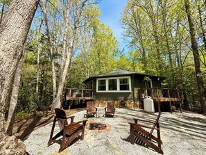 A cabin with a deck, a fire pit, and outdoor seating.