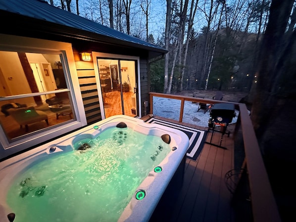 Un jacuzzi en una terraza con vistas a un área boscosa.