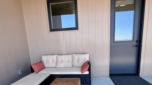 A modern outdoor seating area with a sofa and a small table, a door, and a window. - Phoenix Rising Villa Sauret Ste (Paso Robles)