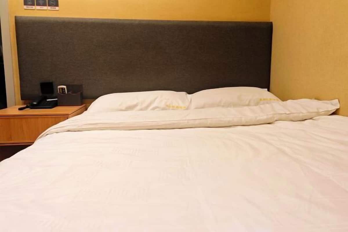 A hotel room with a bed, a nightstand, and a headboard.