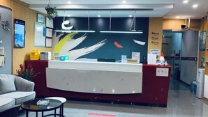 A reception area with a modern desk, a sofa, and a coffee table. - Yi An Hotel (Suzhou)