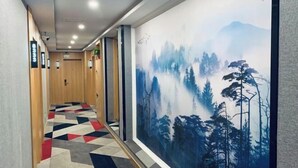 A hallway with a geometric patterned floor, wooden walls, and a large wall mural depicting a forest scene. - Yi An Hotel (Suzhou)