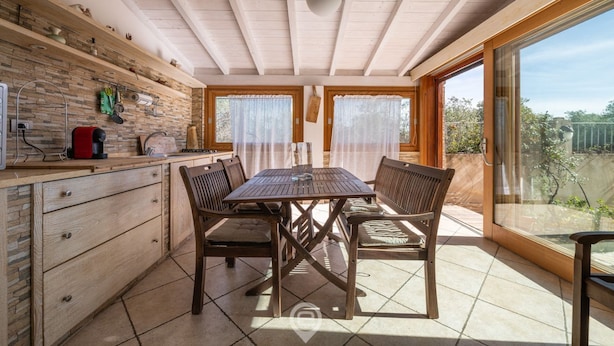 Una cucina con un tavolo e sedie in legno, un muro in mattoni e una grande finestra.