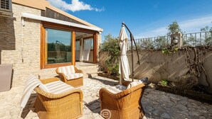 Un patio con mobili in vimini e un'ampia porta-finestra scorrevole che dà su una zona esterna coperta.