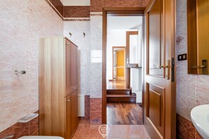 A modern bathroom with a wooden cabinet, a sink, and a shower area.