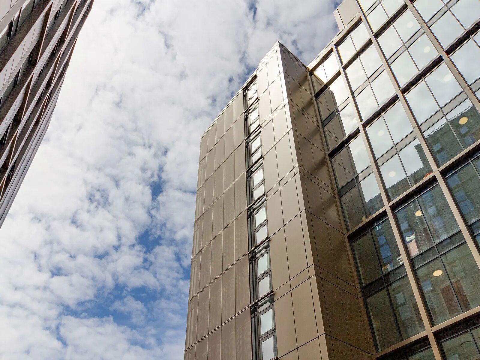 Un moderno edificio de gran altura con fachada de vidrio y una cuadrícula de ventanas.