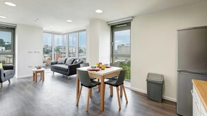 A modern apartment with a dining area, a sofa, and a view of the city. - New Bridewell (Bristol)