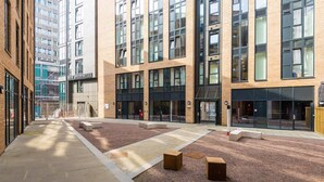A modern building with large windows and a courtyard with seating areas. - New Bridewell (Bristol)