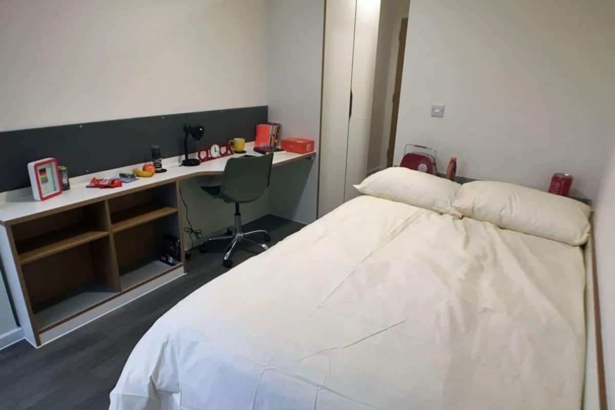 A bedroom with a bed, a desk, a chair, and a wardrobe.