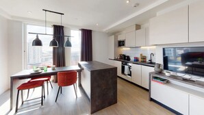 Eine moderne Küche mit Essbereich, integriertem Backofen, Mikrowelle und einem großen Flachbildfernseher.
