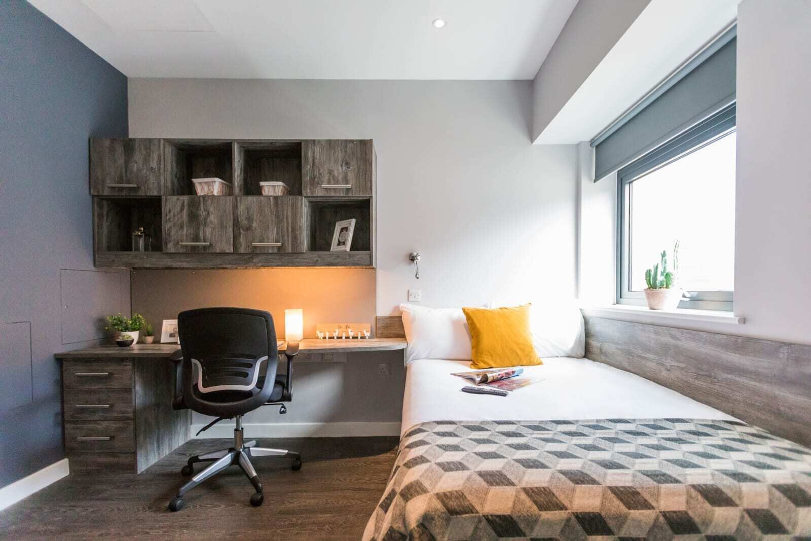 Ein modernes Hotelzimmer mit Schreibtisch, Stuhl und Bett.