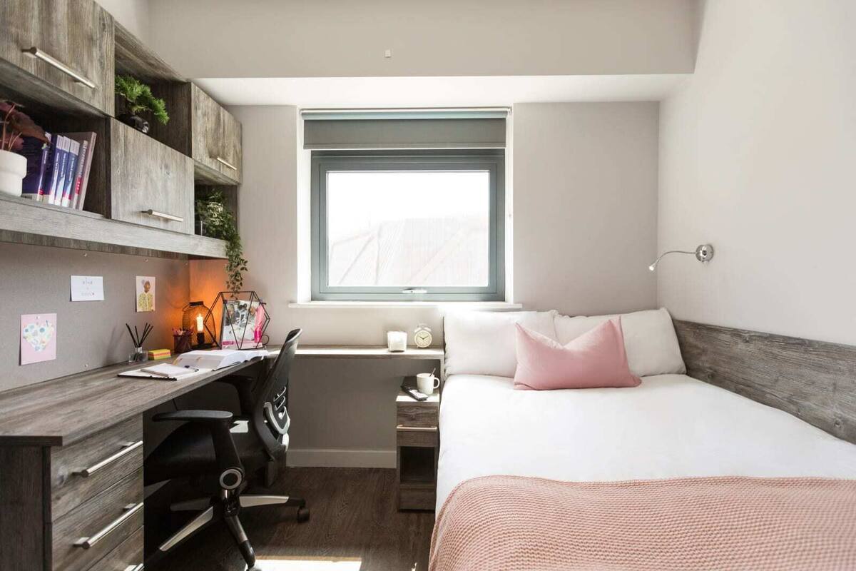 Une chambre à coucher de taille réduite, comprenant un lit, un bureau et une étagère.