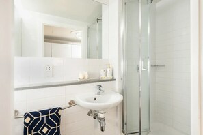 A bathroom with a white sink, a glass shower enclosure, and a towel rack with a patterned towel. - Student Only Radford Mill (Nottingham)