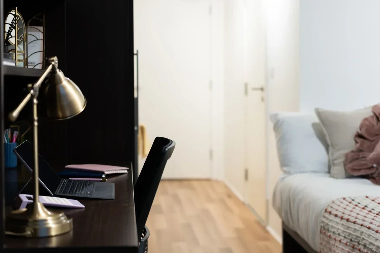 Une chambre à coucher avec un bureau, un ordinateur portable, une lampe et un lit avec des oreillers.