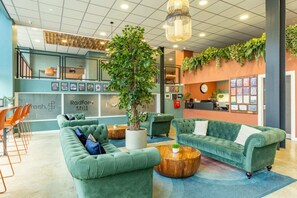 A lobby with green sofas, a coffee table, and a reception desk. - Student Only Radford Mill (Nottingham)