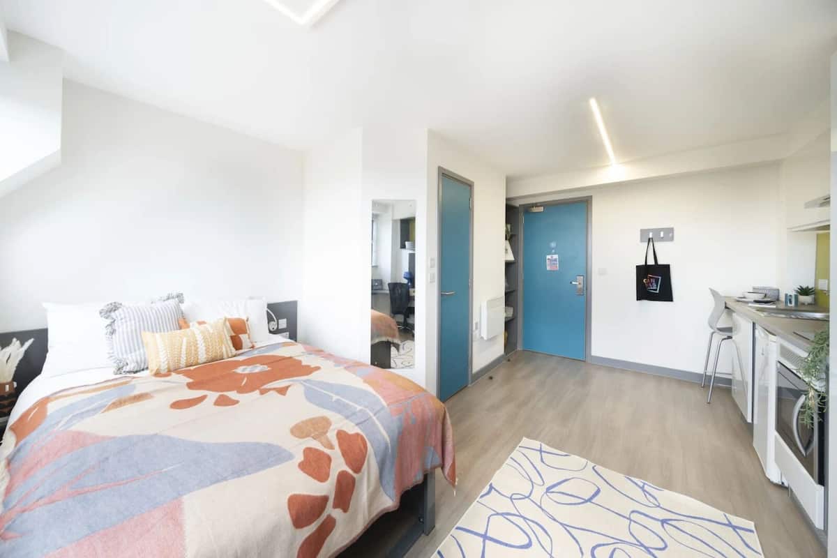 Una habitación de hotel moderna con una cama grande, un escritorio y una kitchenette.