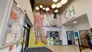 A lobby with a large mural, a reception desk, and a staircase. - For Students Only Canvas Capital House in Southampton (Southampton)