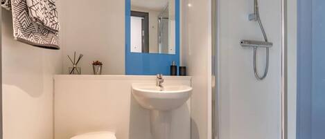 Ein modernes Badezimmer mit Waschbecken, Spiegel und Dusche.