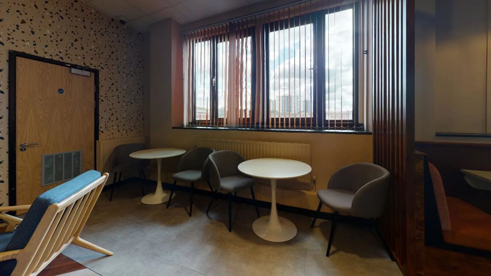 Een kamer met een kitchenette, twee ronde tafels en vier stoelen.
