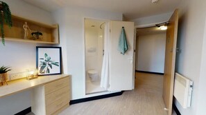 Un baño moderno con ducha, inodoro y lavamanos. Hay una toalla colgada en la pared y un cuadro en el mostrador.